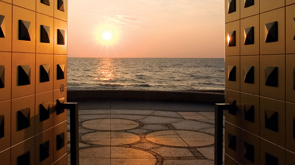 The open doors of Madonna Della Strada a bright, golden, setting sun sits over Lake Michigan.