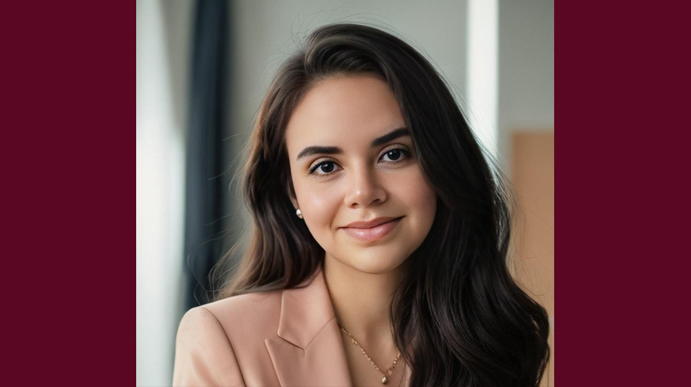 Headshot of a brunette person in a light pink blazer