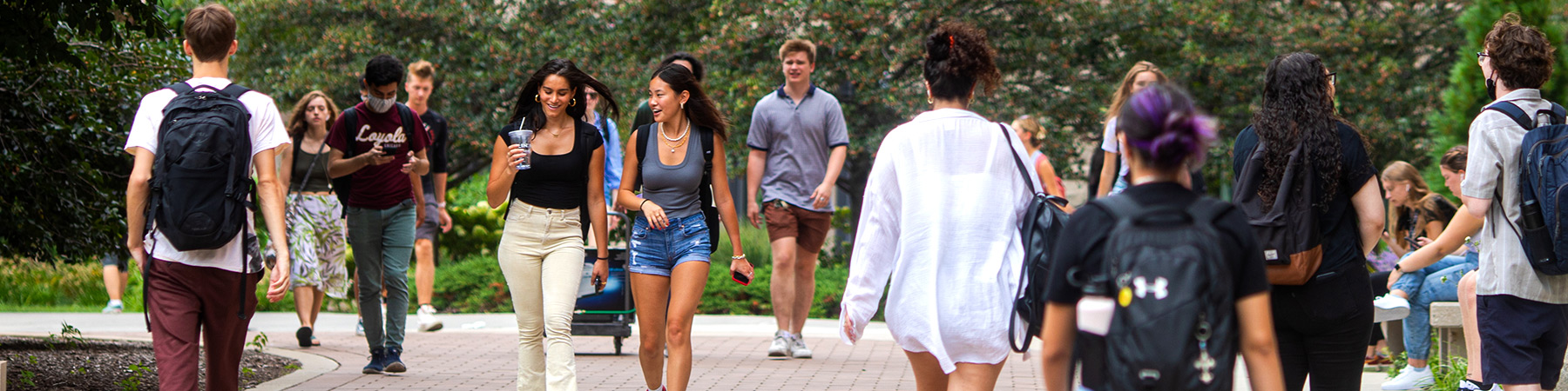 A diverse group of students walk the campus of Loyola in the summer