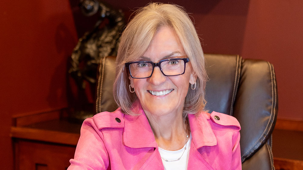 Headshot of Linda Stroh sitting in an office wearing a pink jacket