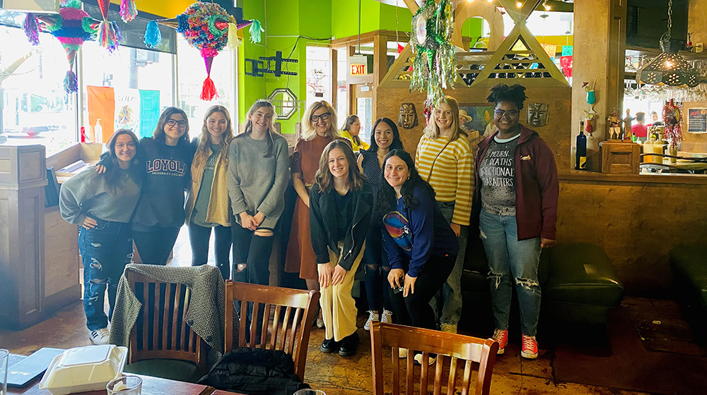  A group of Loyola University Chicago students gather in the lobby of a restaurant and pose for a photo together