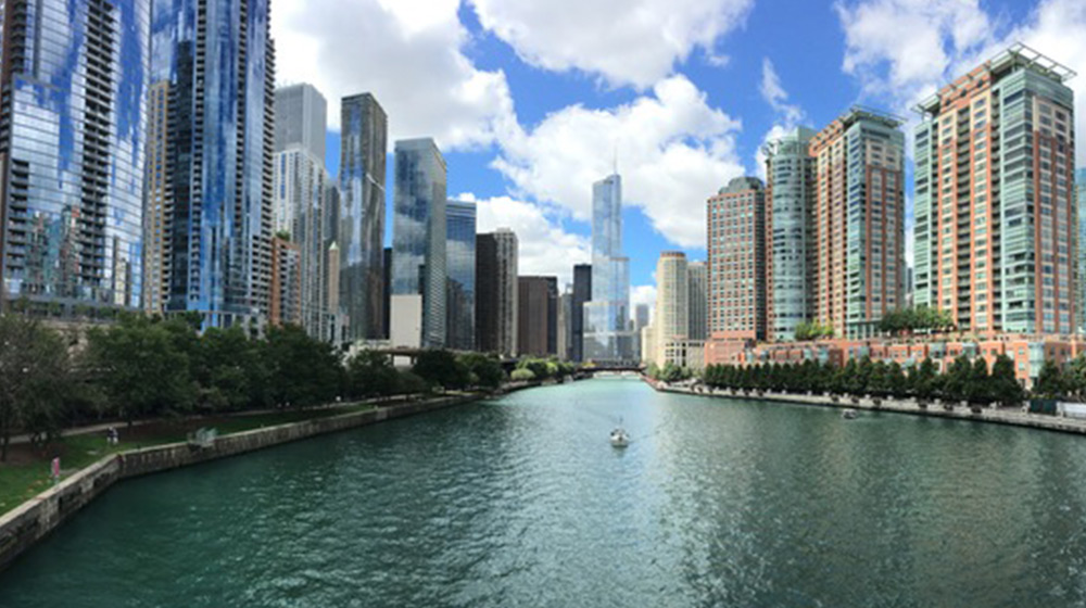 A high up shot of the Chicago river with skyscrapers lining each side on a cloudy but sunny day