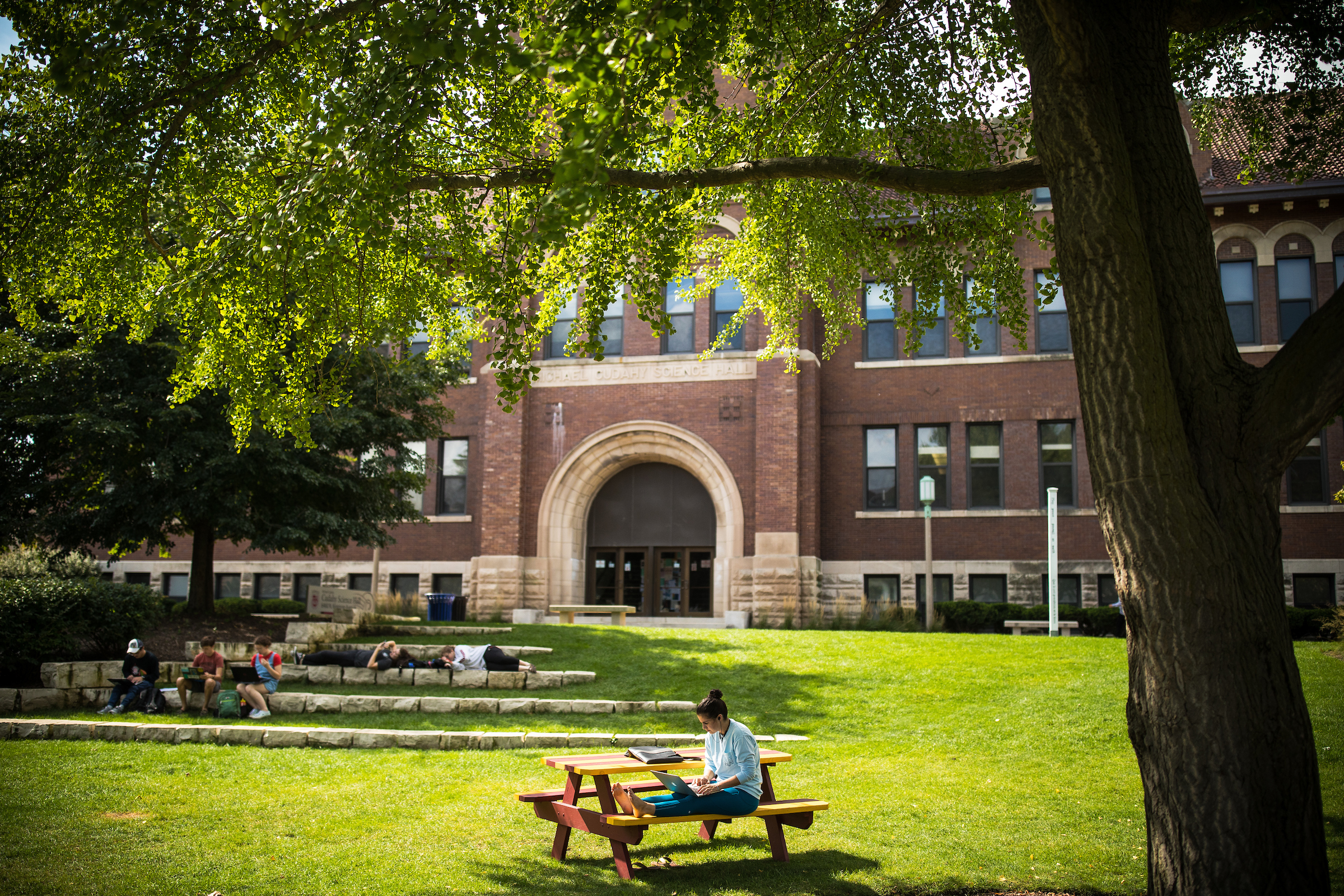 A student sits at an outdoor table on Loyola Chicago's quad